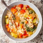 Vegetable rice soup in a bowl with a spoon.