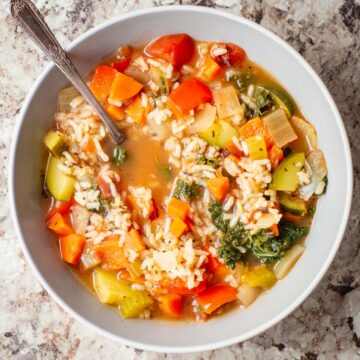 Vegetable rice soup in a bowl with a spoon.