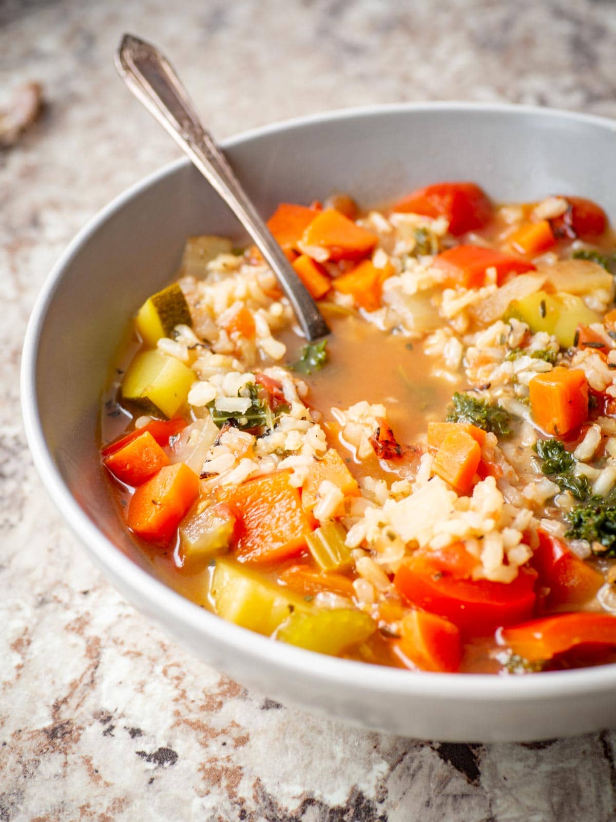 Vegetable rice soup in a bowl with a spoon.