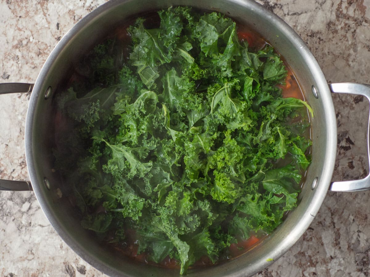Kale added to a pot of soup.