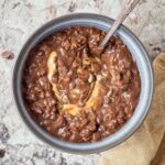 Chocolate oatmeal in a bowl topped with peanut butter.
