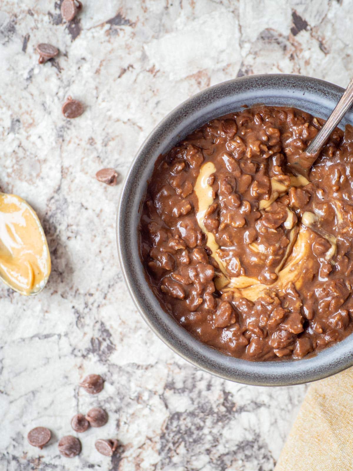 Peanut butter stirred into a bowl of chocolate oatmeal.