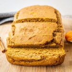 Loaf of pumpkin bread sliced on a cutting board.