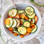 Carrots and zucchini in a bowl topped with dill.