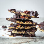 Pecan chocolate bark chunks stacked in a pile.