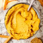 Pumpkin pie hummus in a bowl with a spoon.