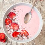 Thick strawberry smoothie bowl topped with berries and coconut.