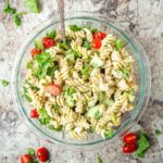 Bowl of pasta salad topped with a pesto dressing.