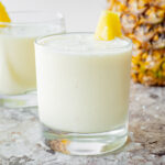 Pina colada without alcohol in a cup garnished with a pineapple wedge.