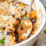 Pulled pork casserole in a baking dish with a serving spoon.