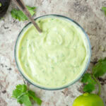 Avocado lime crema in a bowl with a spoon.
