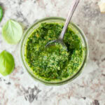 Pesto in a jar with a spoon.
