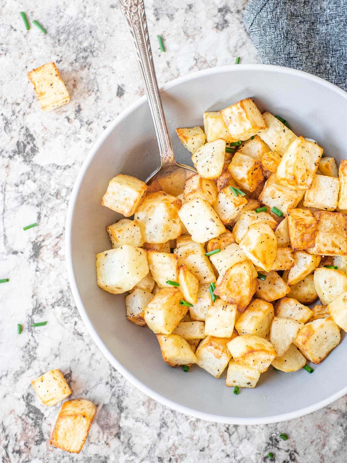 Crispy diced potatoes in a bowl with a spoon.