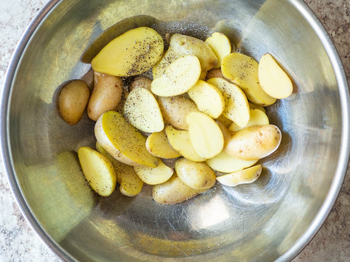 Potatoes mixed with seasoning in a bowl.
