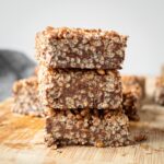 Crisp rice peanut butter chocolate squares stacked on a cutting board.