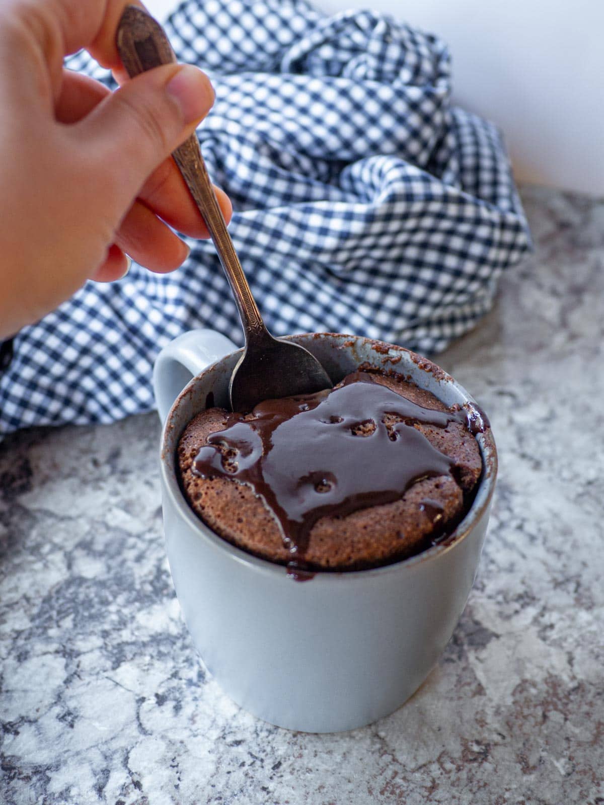Spoon taking a bite from a mug of oat cake.