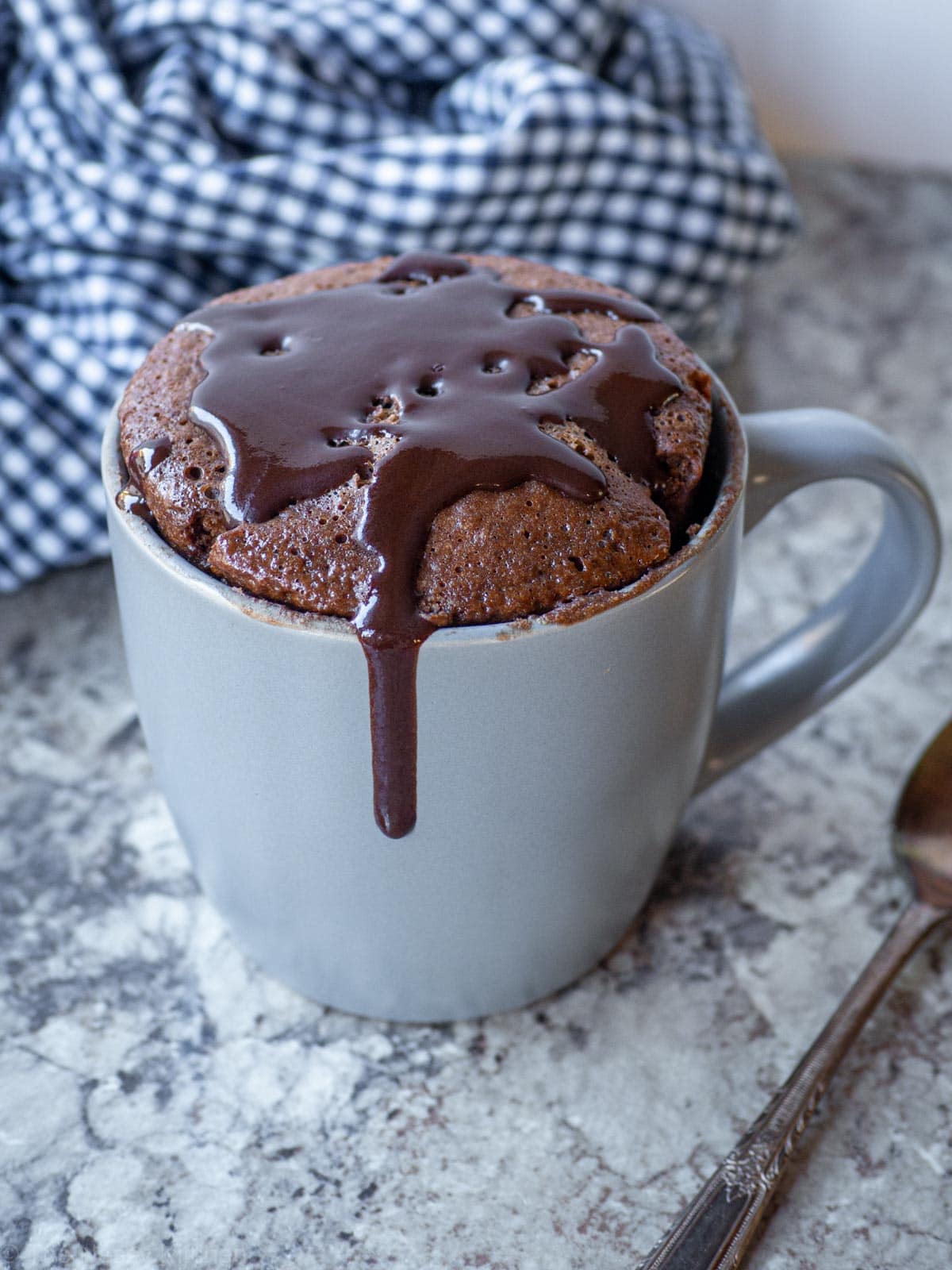 Chocolate mug cake topped with chocolate icing.