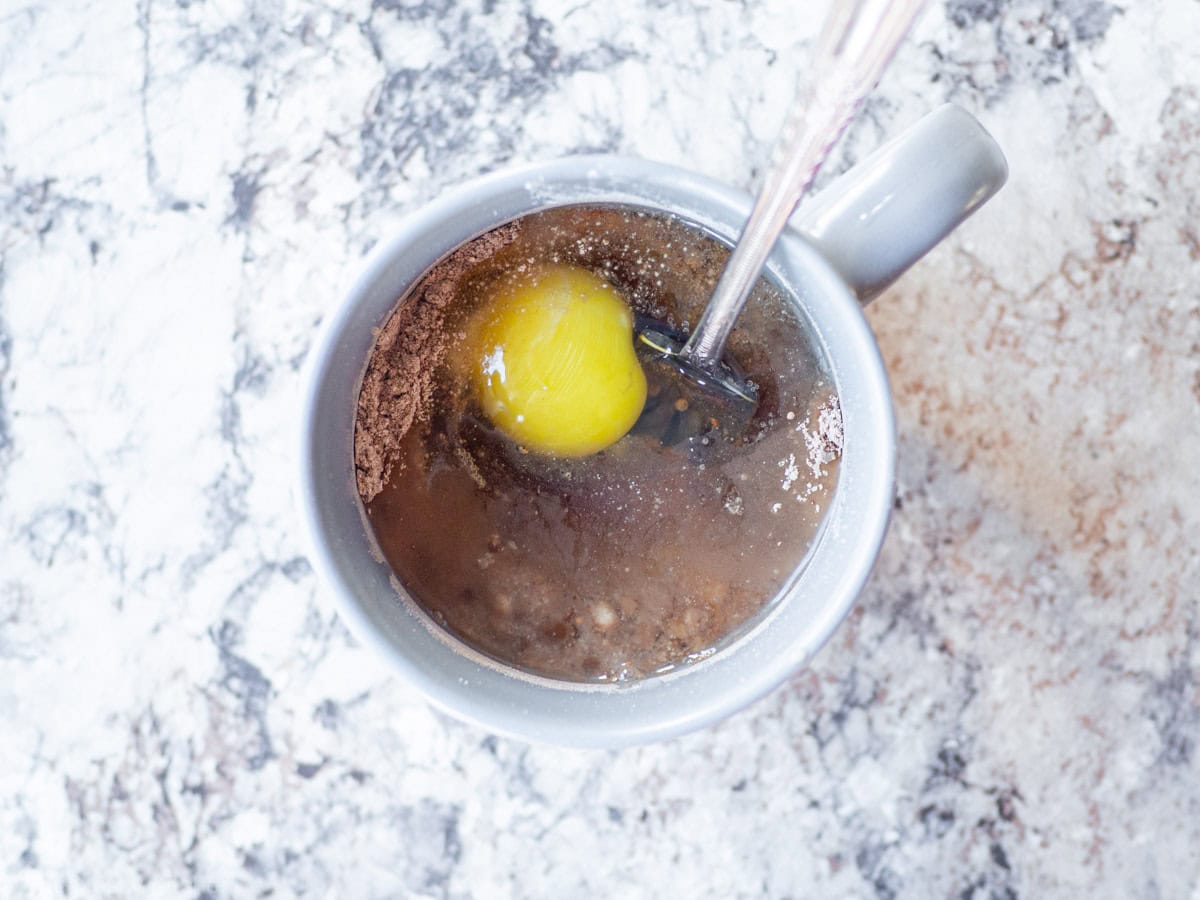 Oat mug cake ingredients being mixed together in a large mug.