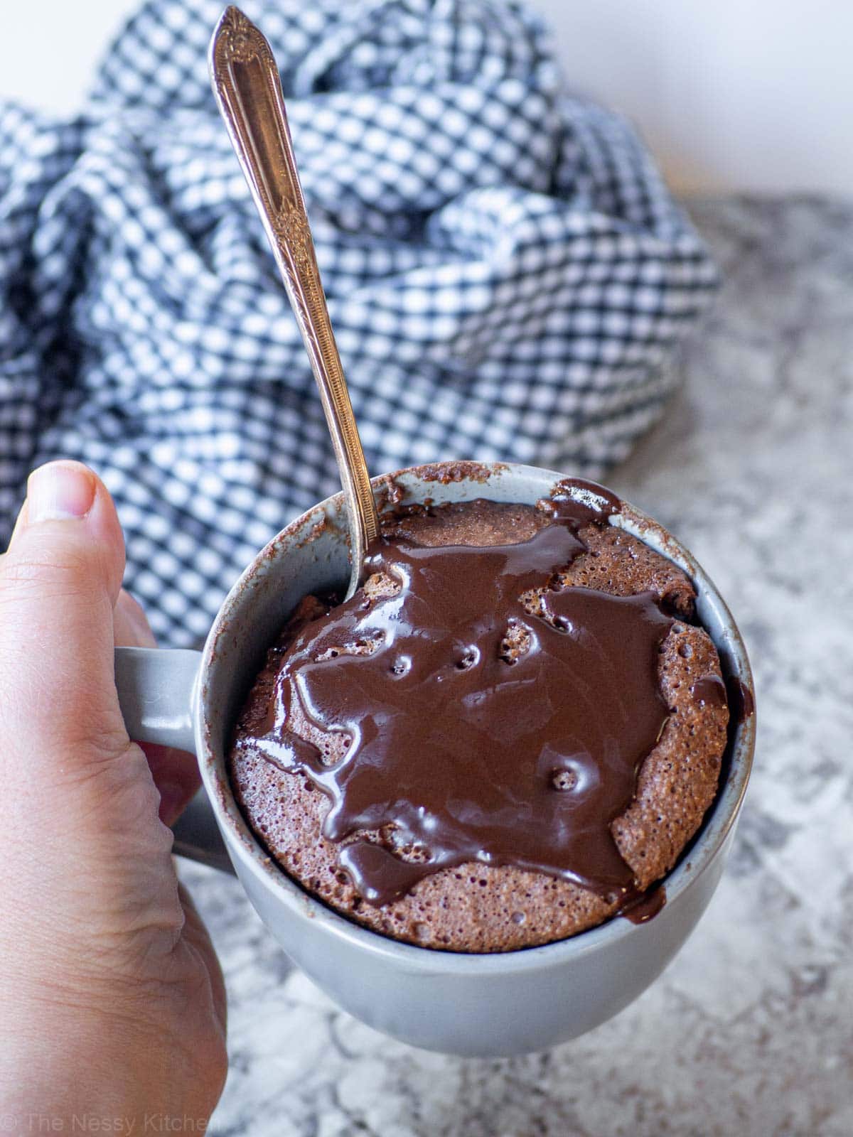 Hand holding up a mug filled with cake.