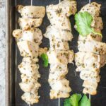 Chicken skewers on a baking sheet.