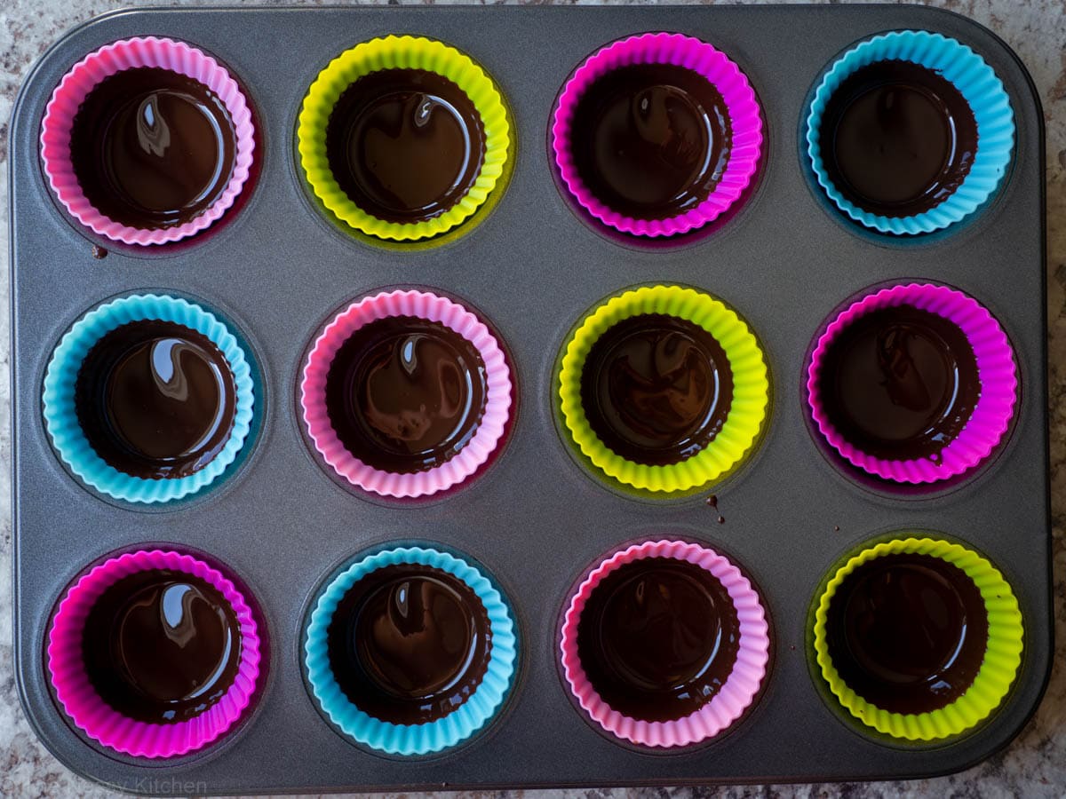 Melted chocolate divided into silicone liners.