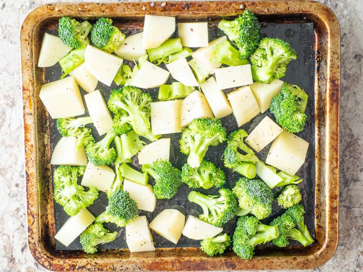 Broccoli and potatoes on a lined sheet pan.