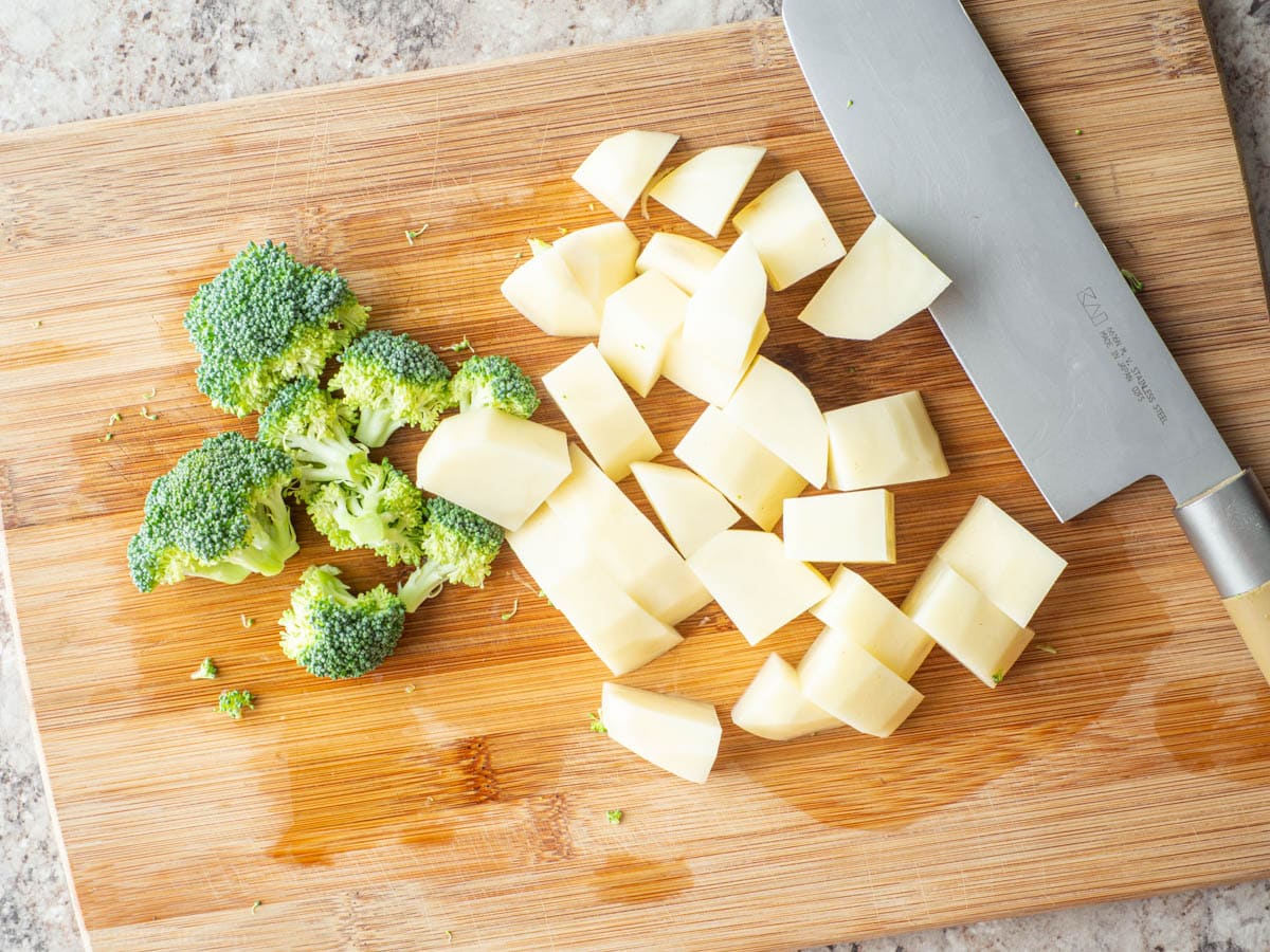 Potatoes and broccoli diced on a cutting board.