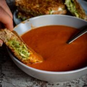 Sandwich being dipped into a bowl of soup.
