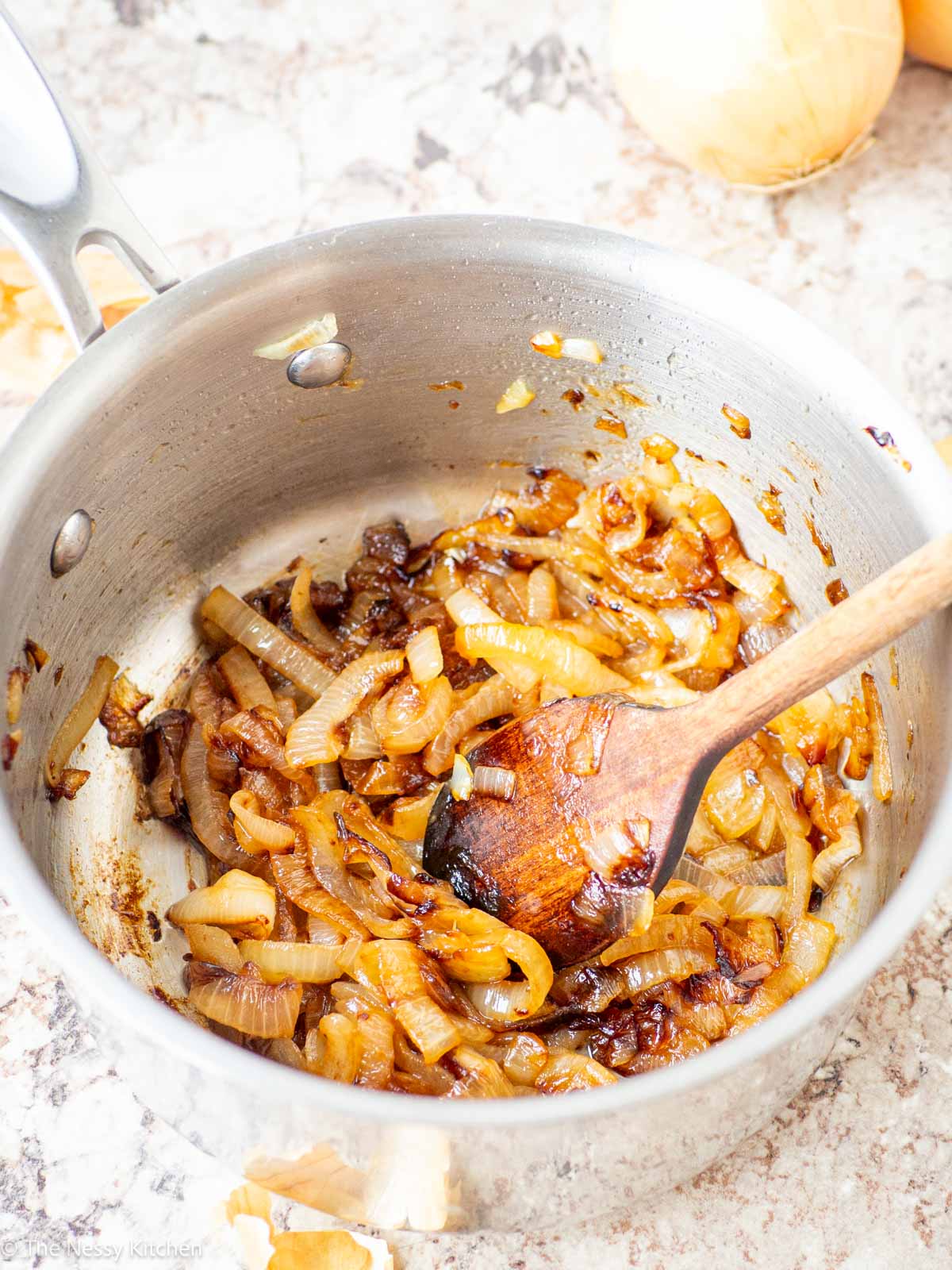 Wooden spoon stirring onions.