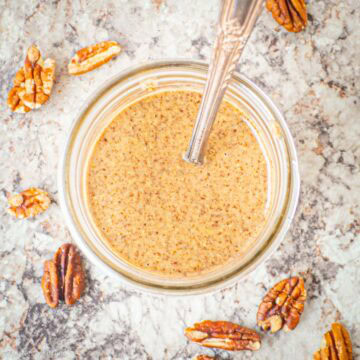 Jar of homemade pecan butter with a spoon in it.