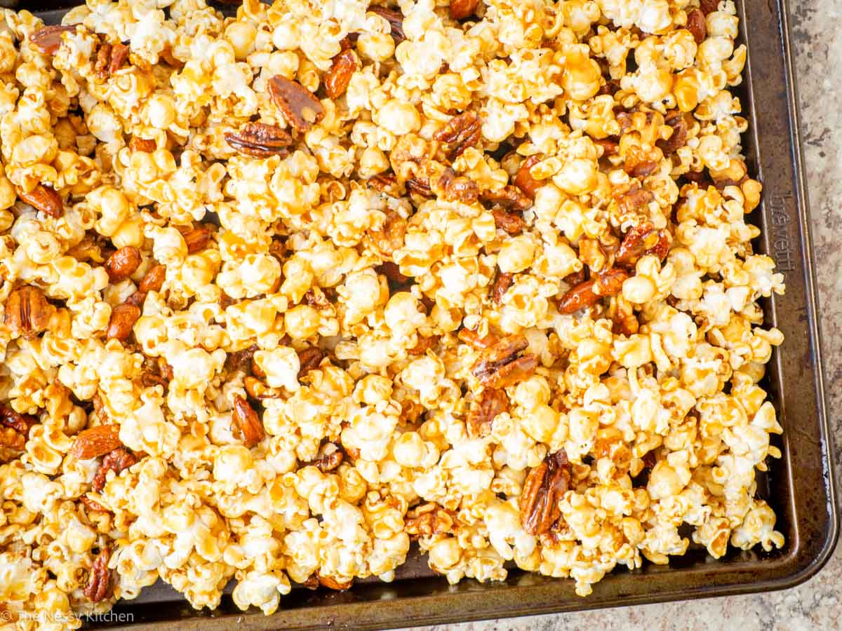 Caramel corn spread out on a cookie sheet to set.