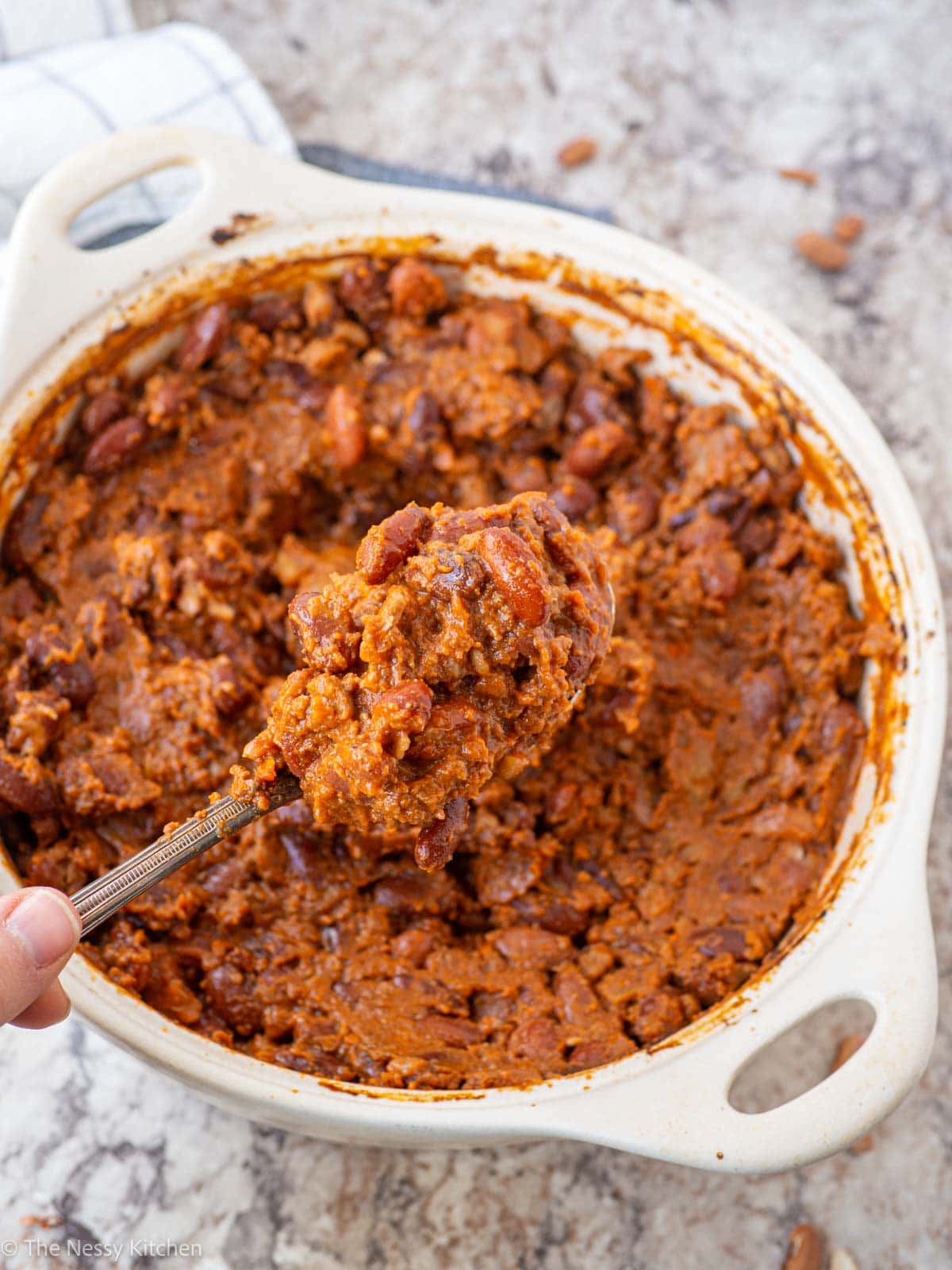 Spoon taking scoops of baked beans.