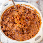 Spoon taking a scoop of hamburger baked beans.