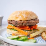 Pork burger on a bun with pickled vegetables.
