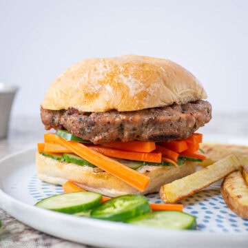 Pork burger on a bun with pickled vegetables.