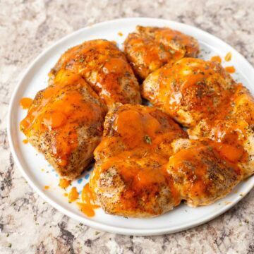 Buffalo chicken thighs on a plate.