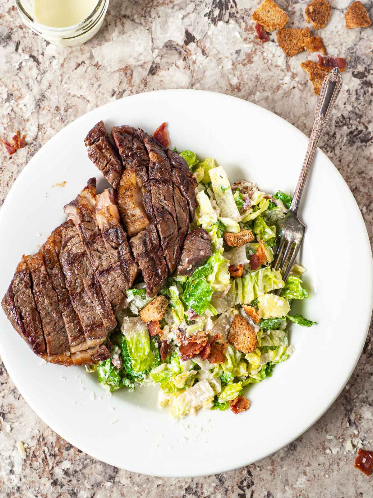 Steak on a plate with Caesar salad.
